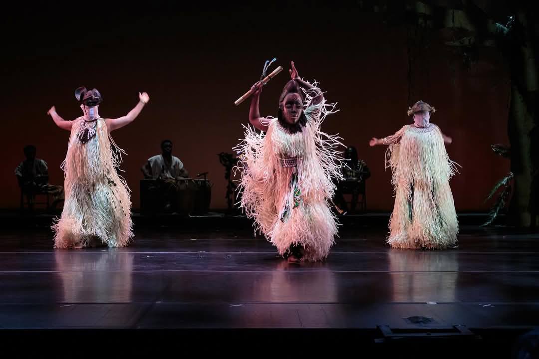 Three masked Juju dancers in raffia costumes on stage at BAM DanceAfrica 2024